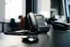 A black desk phone next to the users computer