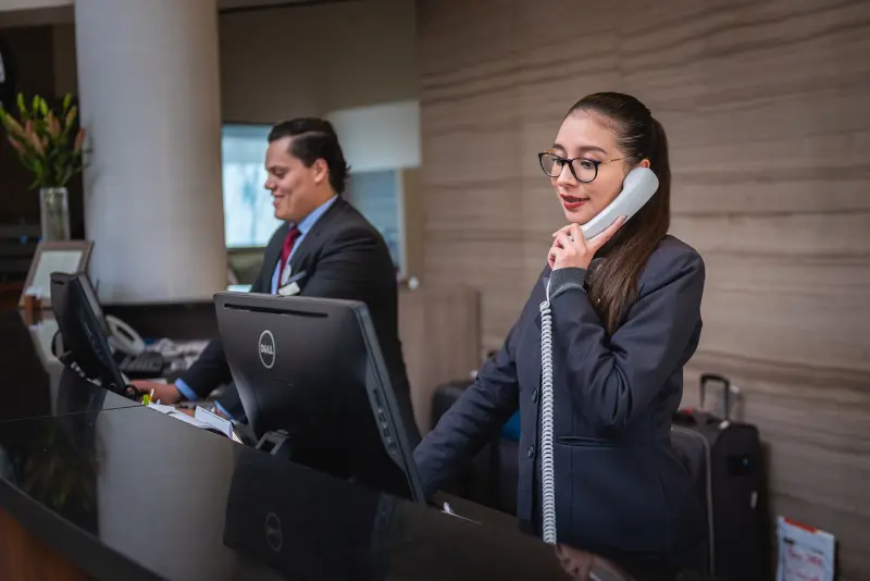 Hotel receptionist at her desk answering a phone call