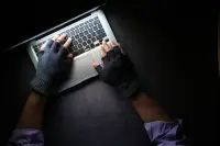 A man using a modern laptop wearing gloves