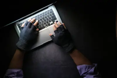 A man using a modern laptop wearing gloves